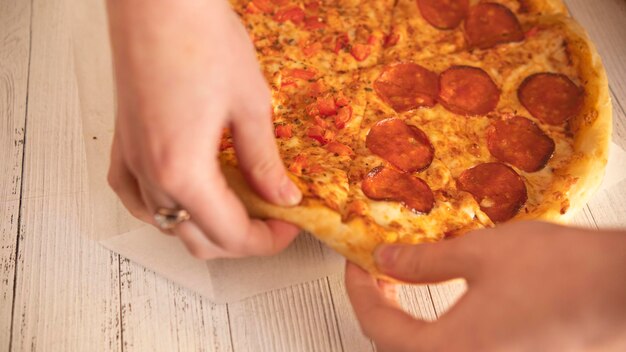 Uma pessoa colocando uma pizza de pepperoni em uma mesa