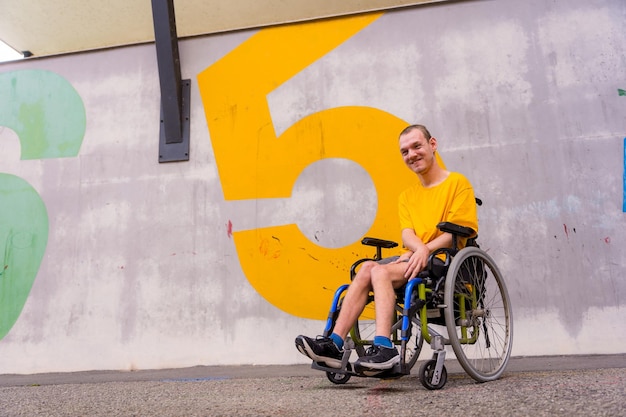 Uma pessoa com deficiência em um parque público em uma cadeira de rodas vestindo uma camiseta amarela