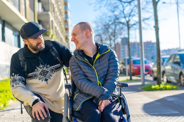 Uma pessoa com deficiência em uma cadeira de rodas com um amigo sorrindo normalidade deficiente