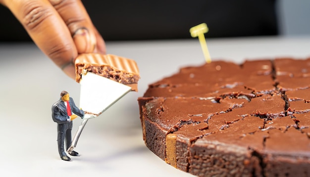 Uma pessoa cortando um pedaço de bolo de chocolate com um pedaço sendo cortado.