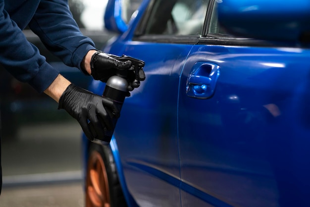 Uma pessoa de serviço de oficina de automóveis aplicando camada de revestimento cerâmico