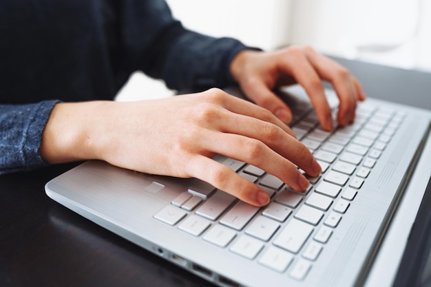 Uma pessoa digitando em um laptop com a palavra computador no teclado.