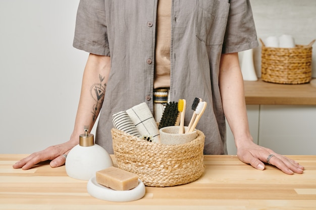 Uma pessoa em pé à mesa com uma cesta com material de cuidados corporais