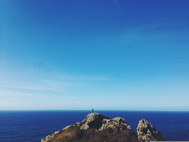 uma pessoa está de pé em uma rocha com vista para o oceano