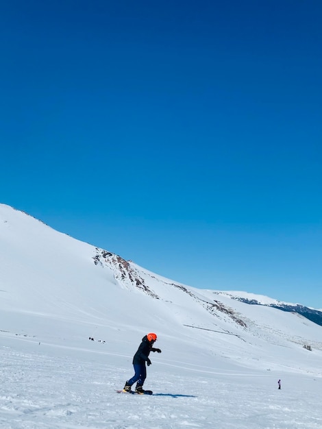 Foto uma pessoa está esquiando em uma montanha coberta de neve com um fundo de céu