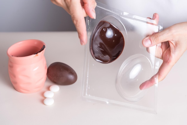 uma pessoa está pintando um ovo de chocolate em um recipiente de plástico