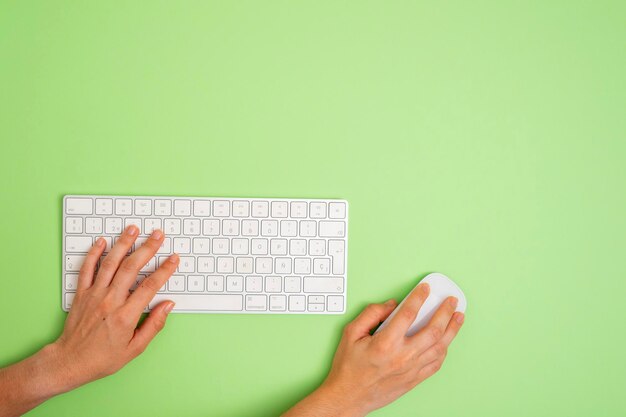 Foto uma pessoa está usando um teclado de computador com um rato em um fundo verde copiar espaço