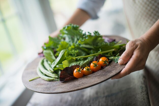 Foto uma pessoa preparando produtos orgânicos frescos em uma cozinha bandeja de vegetais, tomates e verduras