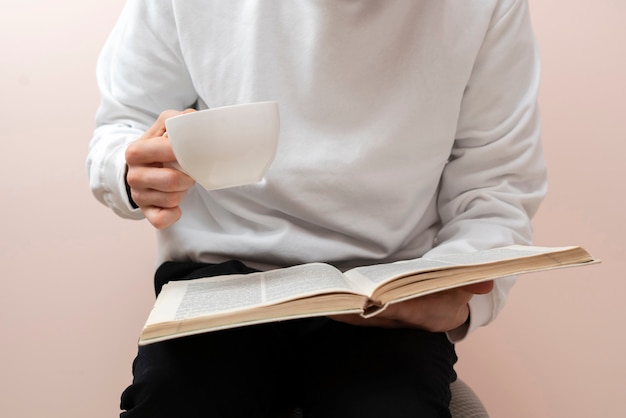 Uma pessoa relaxando em casa, lendo um livro e tomando chá, descansando à noite