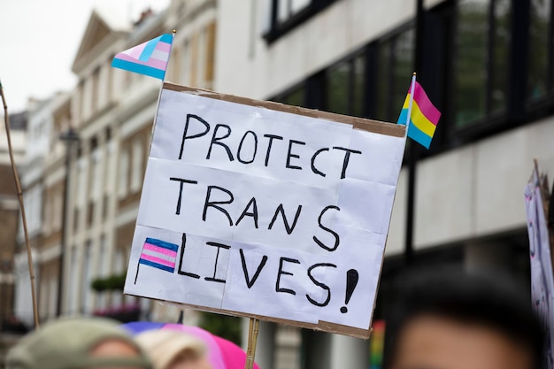 Uma pessoa segurando um cartaz lendo protege o banner de vidas trans