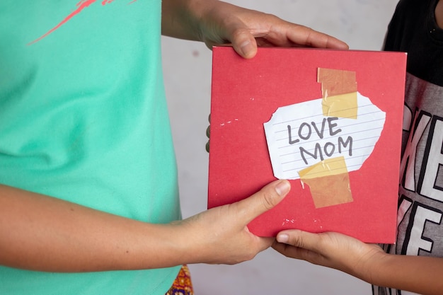 Uma pessoa segurando um livro vermelho que diz amor mãe.