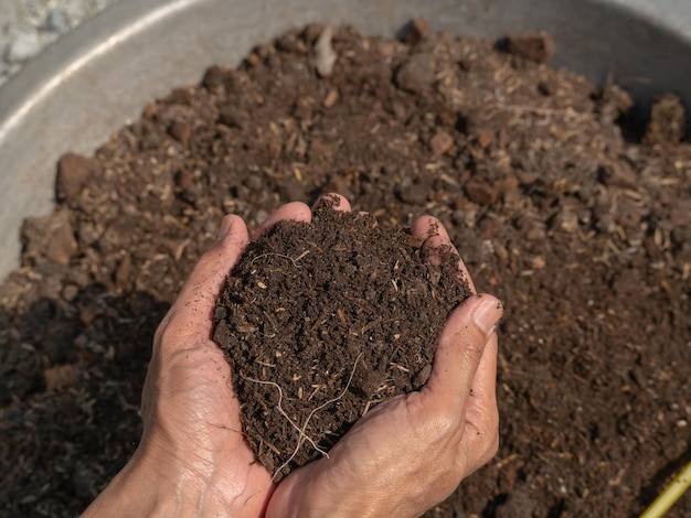 Uma pessoa segurando um punhado de terra em um recipiente