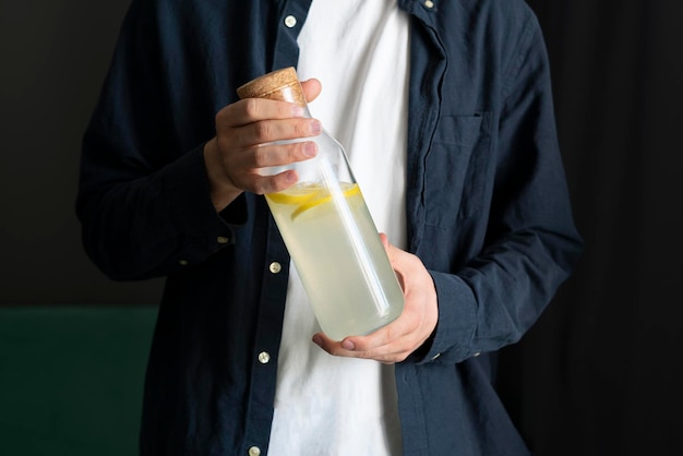 Uma pessoa segurando uma garrafa com coquetel de mojito de limão de verão