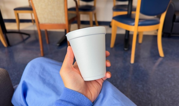 Uma pessoa segurando uma xícara de café em um quarto de hospital.