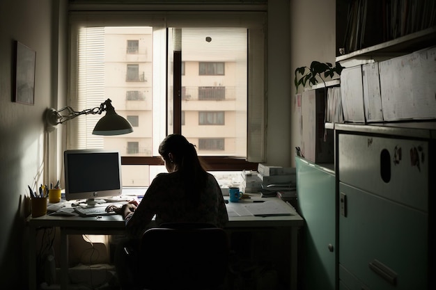 Foto uma pessoa sentada em um computador em um escritório interno cercado por um design de interiores moderno uma janela permite a entrada de luz natural no espaço de trabalho ai gerado