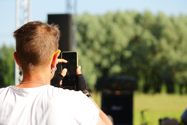 Uma pessoa tira fotos de um divertido evento de rua em um smartphone em um dia quente de verão