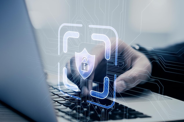 Uma pessoa trabalhando em um laptop com uma sobreposição de conceito de holograma de segurança digital em um fundo desfocado tema criativo de segurança cibernética