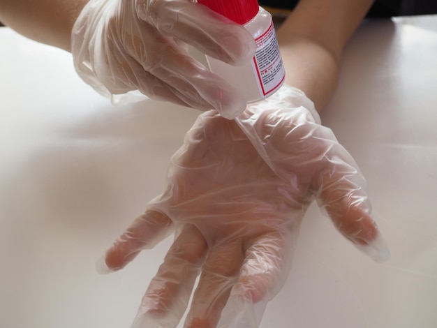 Uma pessoa usando uma luva está usando um frasco de desinfetante para as mãos.
