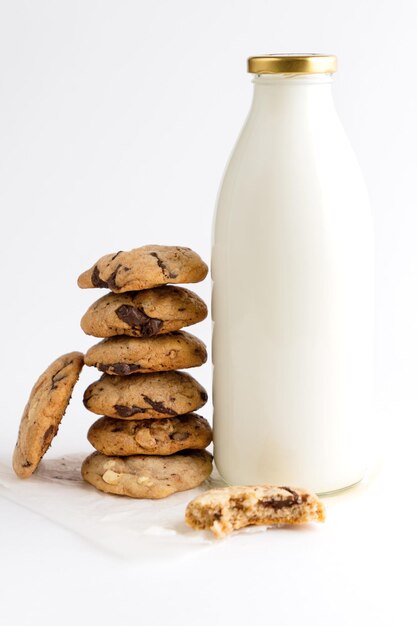 Uma pilha de biscoitos caseiros com pedaços de chocolate ao lado de uma garrafa de leite