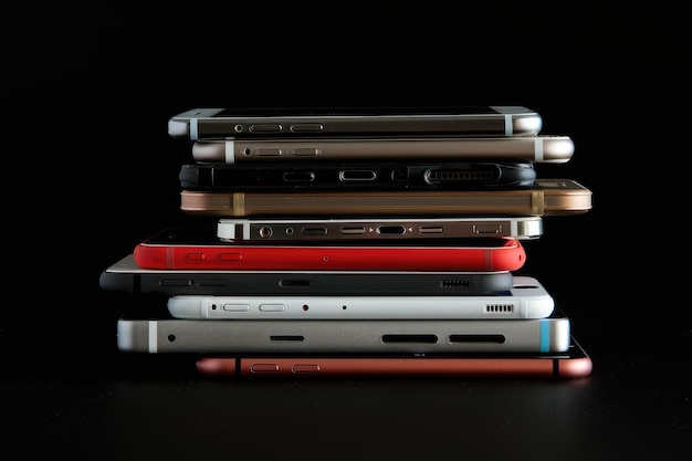 Uma pilha de diferentes smartphones isolados em um fundo preto