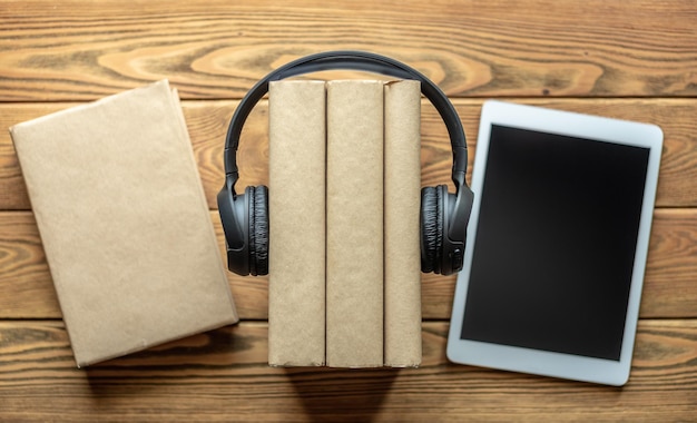 Foto uma pilha de livros com fones de ouvido e tablets em fundo de madeira o conceito de educação tecnológica moderna e o estudo de livros