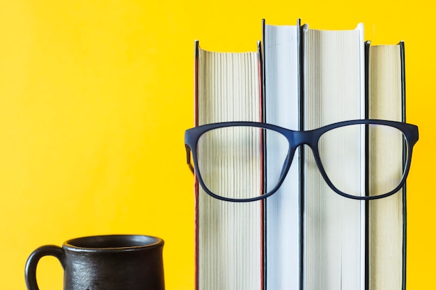 Uma pilha de livros com óculos é uma imagem do rosto de uma pessoa