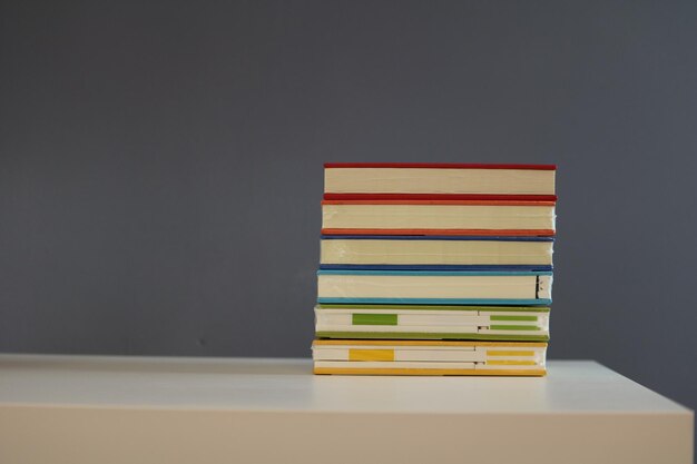 Uma pilha de livros na mesa contra a parede