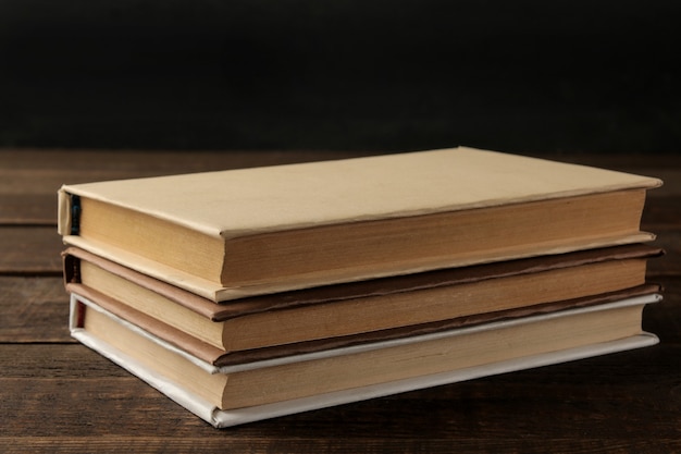 Uma pilha de livros sobre uma mesa de madeira marrom e sobre um fundo preto. Livros velhos. Educação. escola. estude
