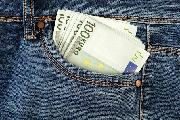 Uma pilha de notas de 100 euros no bolso do jeans Dinheiro no bolso da frente do jeans O conceito de riqueza em dinheiro de investimento e espaço de lucro