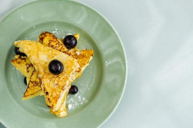 Uma pilha de panquecas com uma pitada de açúcar refinado e mirtilos no café da manhã