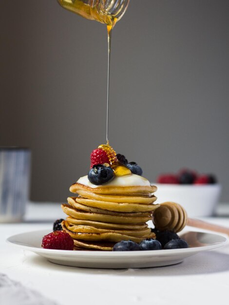 Foto uma pilha de panquecas doces com frutas e mel no café da manhã