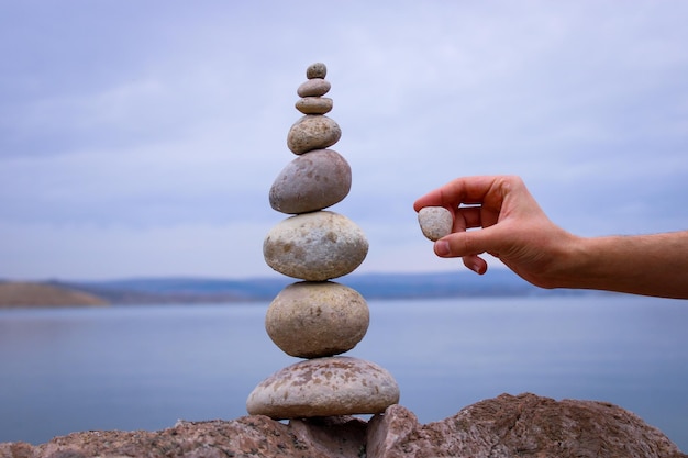 Foto uma pilha de pedras com a mão de uma pessoa segurando uma pilha de pedras.