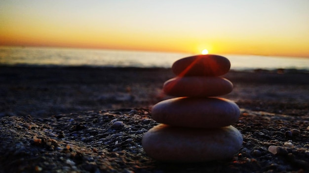 Foto uma pilha de pedras na praia durante o pôr-do-sol