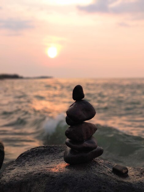 Foto uma pilha de pedras na praia durante o pôr-do-sol