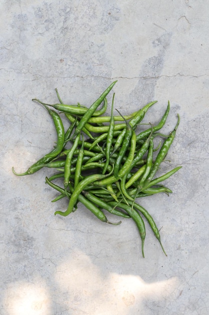 Uma pilha de pimenta verde em uma superfície de concreto