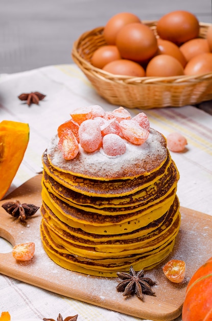 Uma pilha de punkcakes caseiros da abóbora com açúcar pulverizado no kumquat superior e cristalizado.