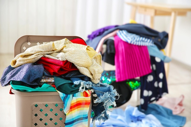 Uma pilha de roupas em um cesto de roupa de plástico dentro de casa