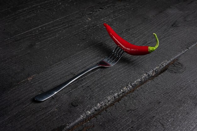 Uma pimenta vermelha em um garfo em uma mesa preta