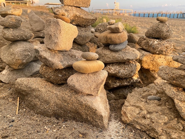 Uma pirâmide de pedras empilhadas umas sobre as outras na praia e areia com pequenos naturais