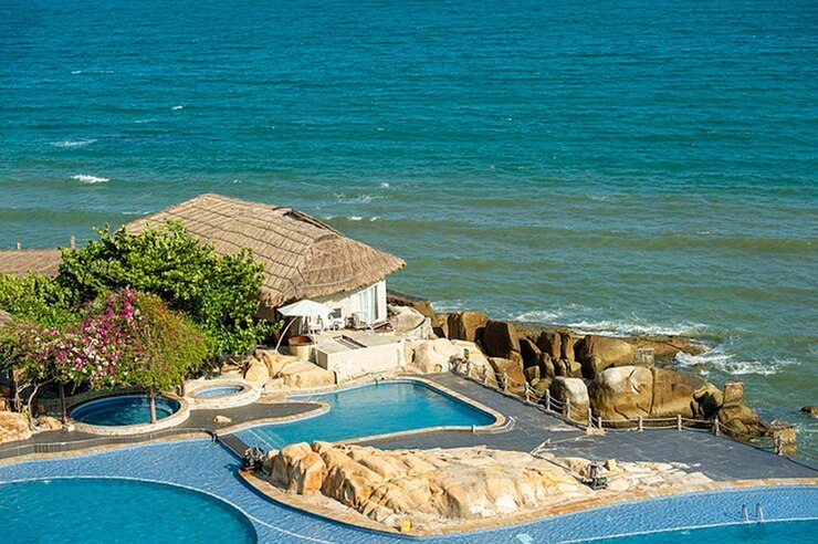 Foto uma piscina com uma casa que tem uma praia ao fundo