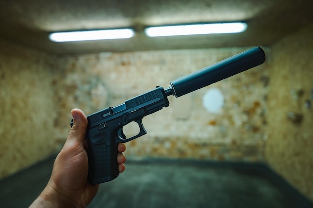 Uma pistola com um silenciador na mão de um homem em um campo de tiro