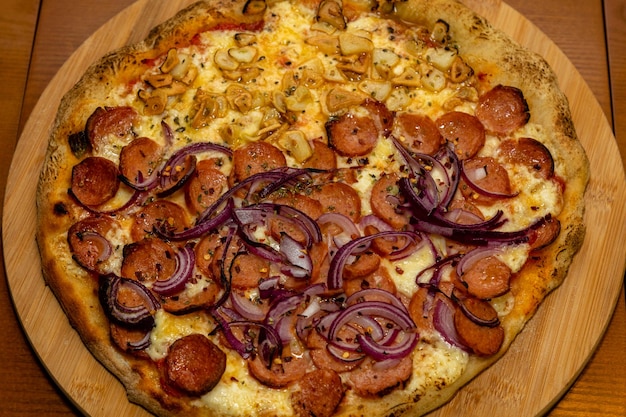 Uma pizza com cebola roxa e linguiça