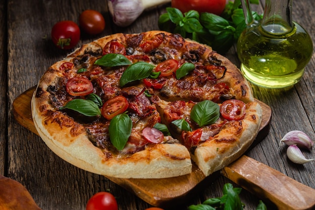 Uma pizza com tomate e manjericão em uma tábua de madeira