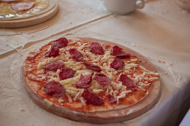 Uma pizza de linha em uma tábua de corte de madeira polvilhada com farinha