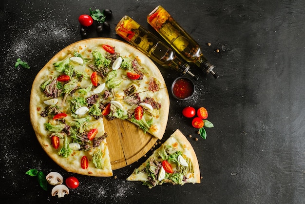 Uma pizza vegetariana com legumes e ervas em fundo preto