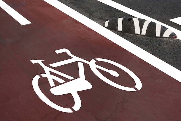 Uma placa branca de ciclovia em uma superfície de asfalto de uma estrada municipal na zona de segurança para bicicletas em primeiro plano