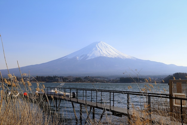 Uma ponte de madeira se estende para o lago com vista para o Monte Fuji.