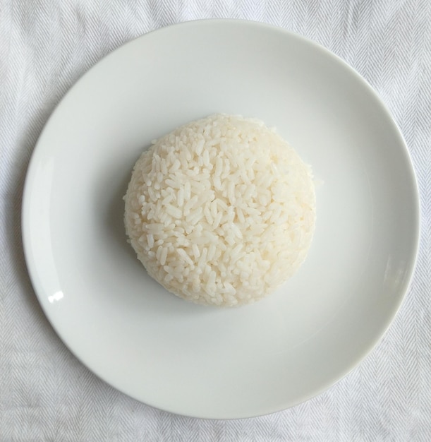 Foto uma porção de arroz branco em prato branco servido em um pano de mesa branco