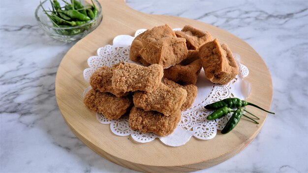 Foto uma porção de fried chicken nuggets e tofu frito servido com pimenta caiena em bandeja de madeira