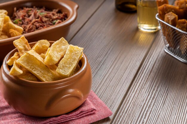 Uma porção de mandiocas fritas em uma mesa de madeira tradicional comida brasileira